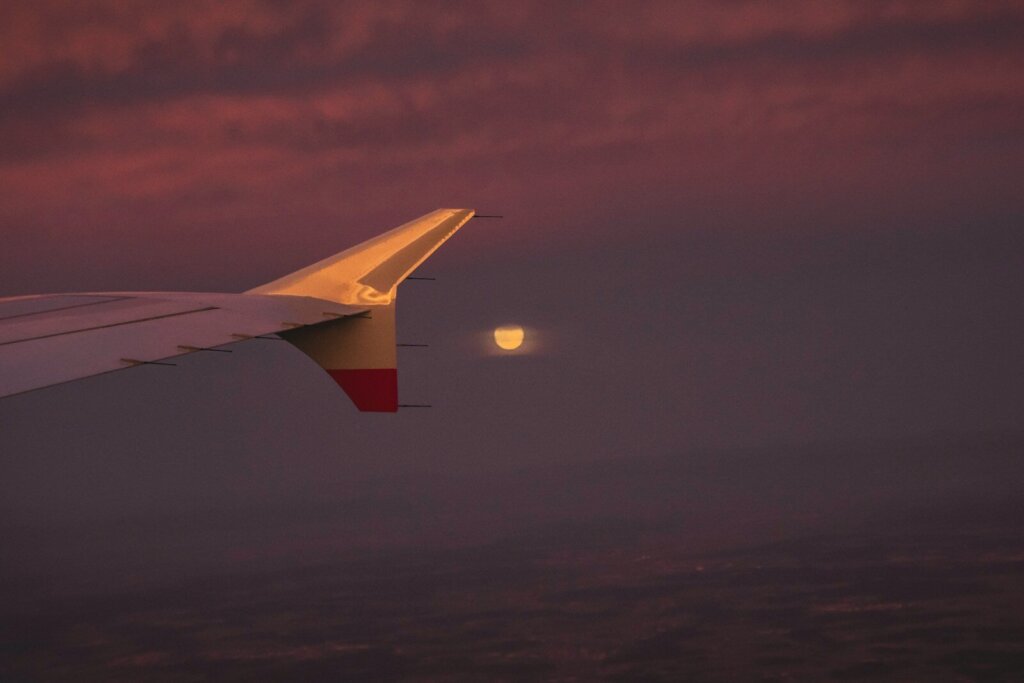 A view of the wing of an airplane with the moon in the distance