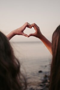 two people making a heart shape with their hands